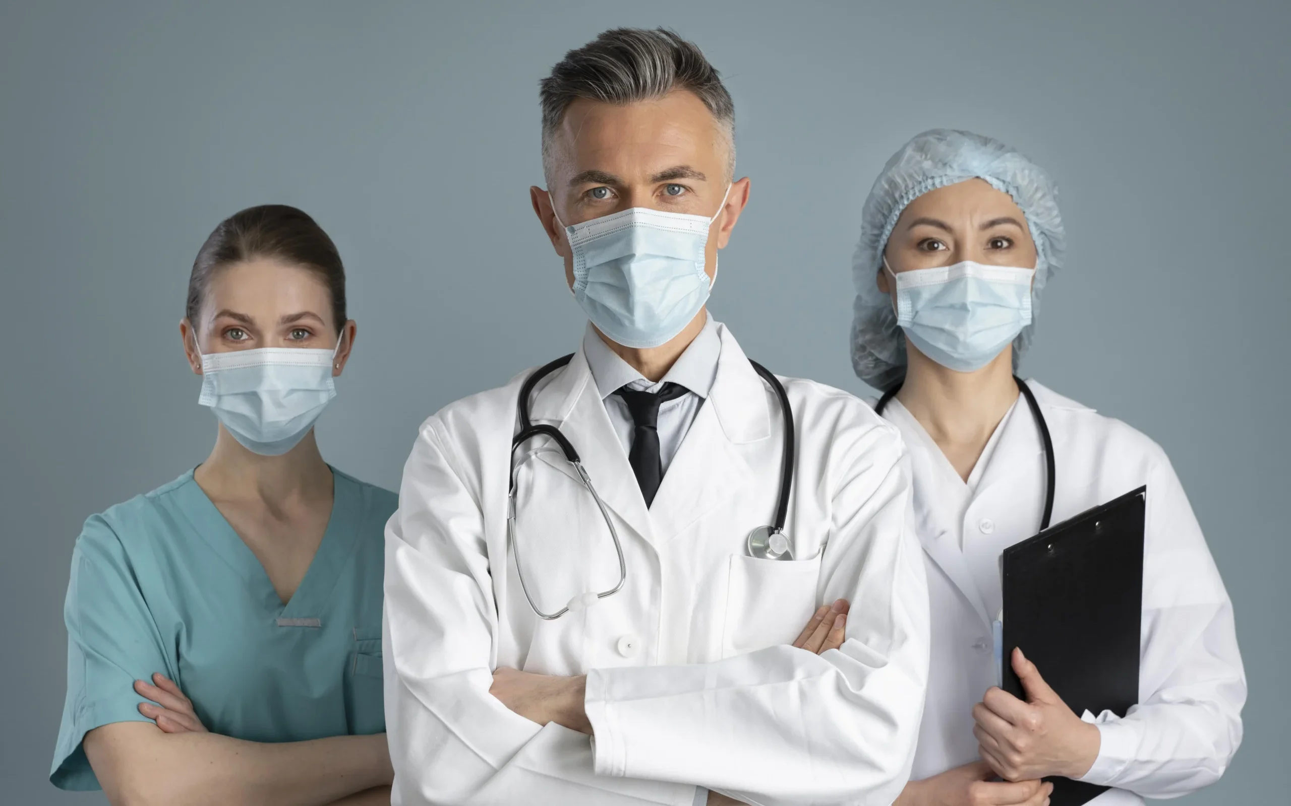 three medical professionals in masks, standing confidently representing professionalism, collaboration and teamwork in healthcare